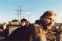 Молодой человек с бородой и девушка на крыше среди труб и антенн.